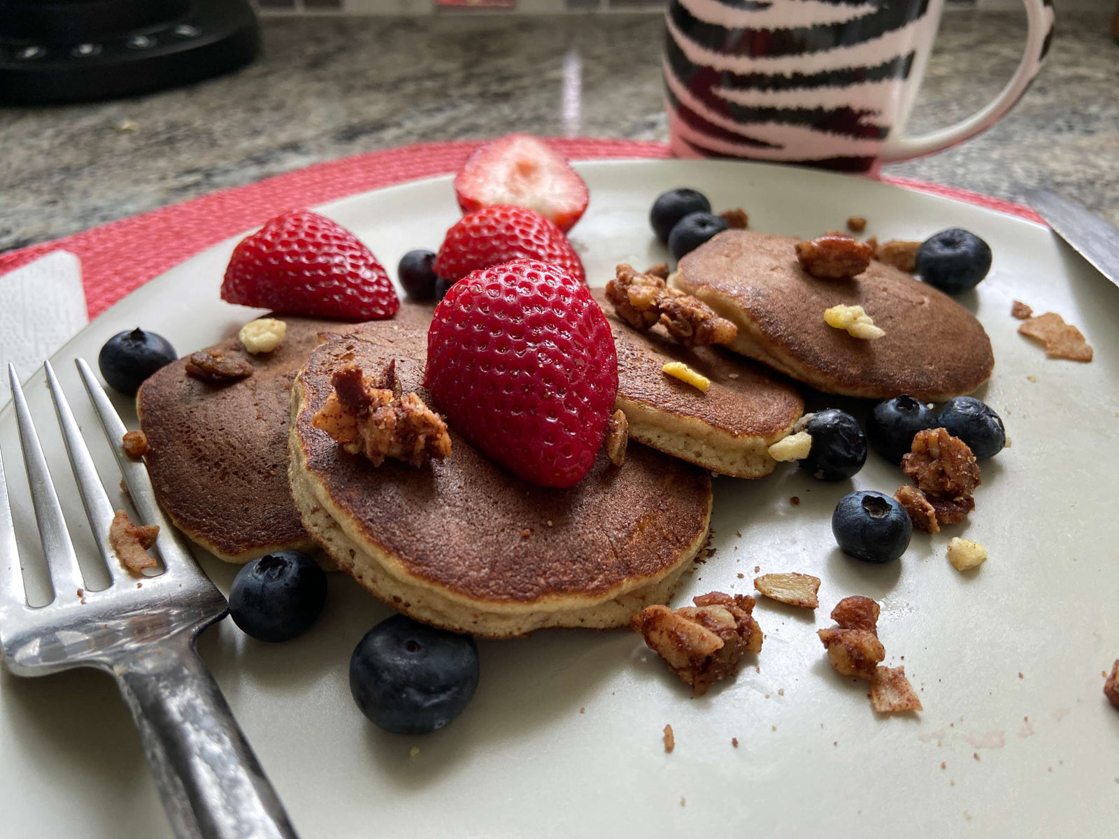 Photo of a stack of gluten-free, grain-free pancakes topped with strawberries and blueberries