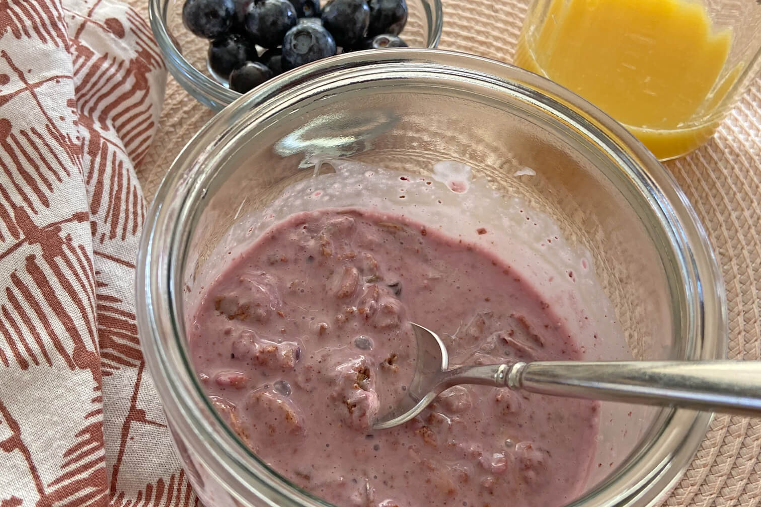 Photo of a glass jar with overnight granola in it, made with yogurt, berries and JuNūla Just Nuts Granola