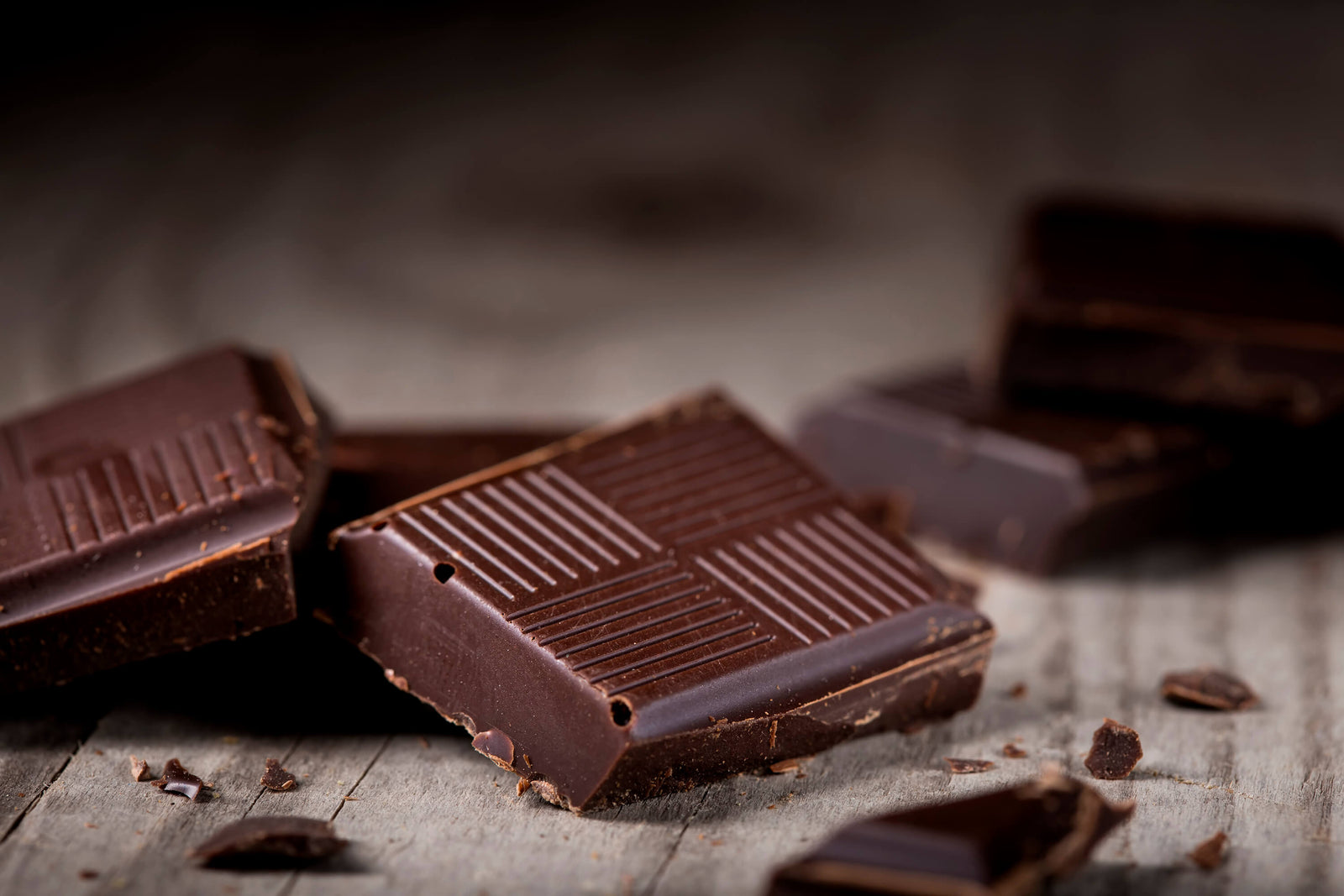 A picture of squares of dark chocolate on a wood cutting board, ready to be added to Just Enough Chocolate JuNula just nuts granola gluten free, grain free, low carb granola