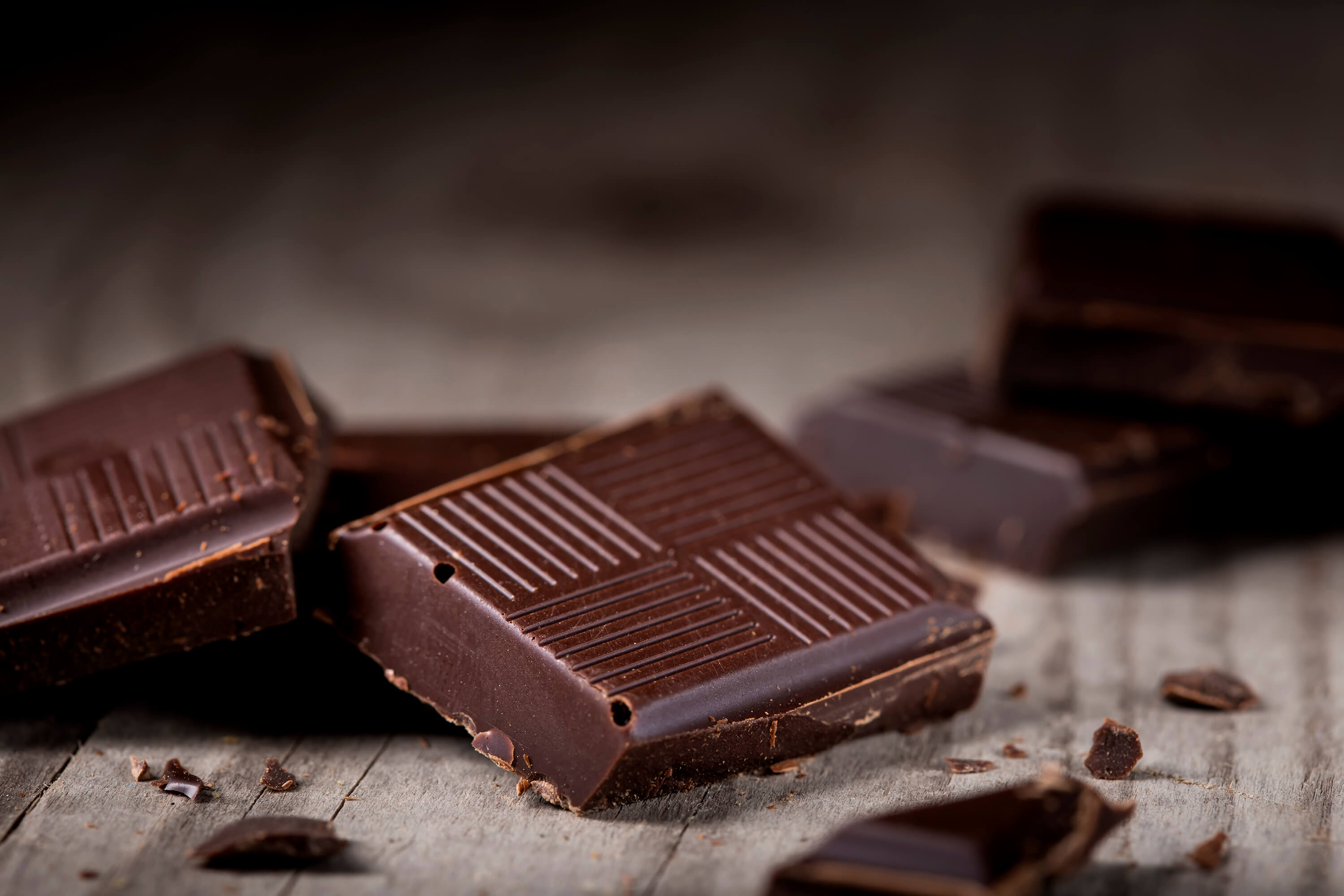 A picture of squares of dark chocolate on a wood cutting board, ready to be added to Just Enough Chocolate JuNula just nuts granola gluten free, grain free, low carb granola