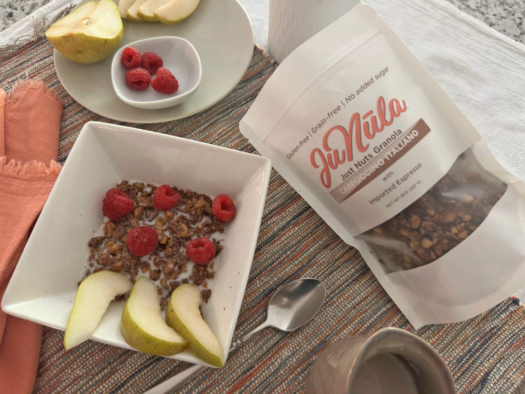 Bowl of cappuccino Italiano granola with pears and raspberries next to a bag of JuNūla granola on a table.