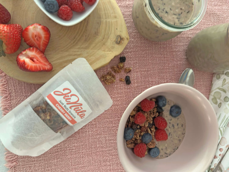 Breakfast scene with a bowl of granola, berries, and a 2oz package of Cherry Berry granola on a pink tablecloth.