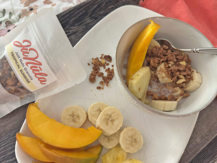 Bowl of Tropical Sunrise granola with mangoes, bananas, and pineapple on a tray